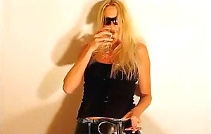 Blonde in jeans pees in wine glass  
